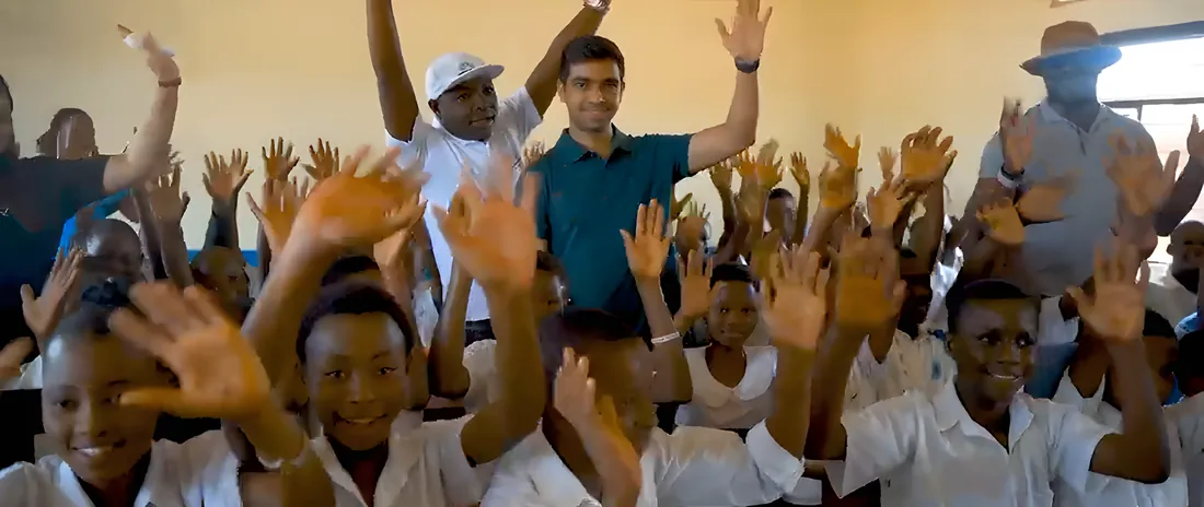 Pupils and visitors in a Kisengo classroom raise their hands